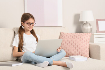 Girl with laptop and books on sofa at home