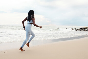 Young woman enjoying running on beach in the morning on summer day