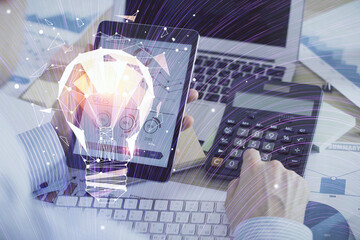 Double exposure of man's hands holding and using a digital device and bulb hologram drawing. Idea concept.