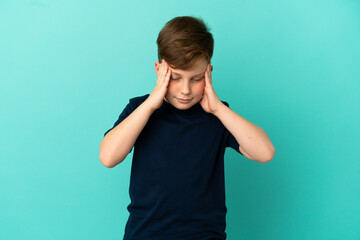 Little redhead boy isolated on blue background with headache