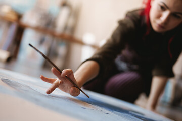 Young woman artist painting in studio