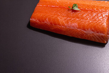 Fresh raw salmon or trout sea fish fillet on black stone background
