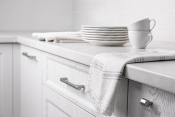 Soft kitchen towel and dishware on countertop indoors, space for text