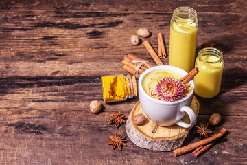 Golden turmeric milk with ice on bright yellow background