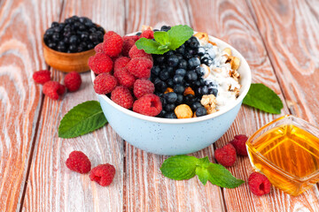 Granola with fresh berries and yoghurt on a wooden background. Healthy breakfast in the morning. Сlose-up.