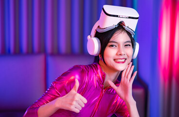 Young asian woman is using virtual reality headset. Neon light studio portrait. Concept of virtual reality, simulation, gaming and future technology.Asian woman play game in bedroom.