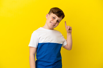 Little redhead boy isolated on yellow background showing and lifting a finger in sign of the best