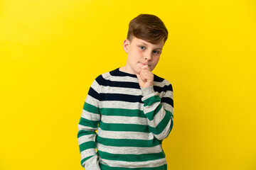 Fototapeta premium Little redhead boy isolated on yellow background having doubts and thinking