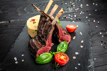 Rack of lamb with couscous decorated with basil and cherry tomatoes on wooden background. banner,...