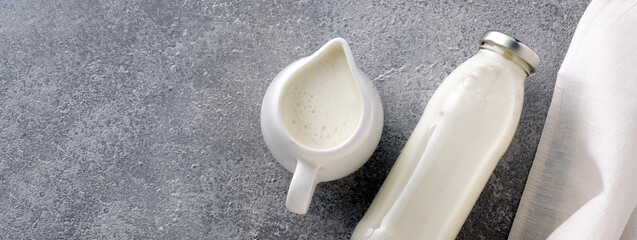 Organic milk in a milk jug and bottle on a gray background with copy space, banner.
