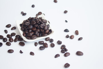 Coffee beans in small white dish on white background. beside view