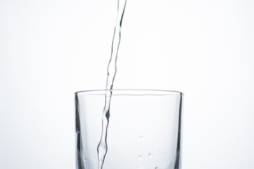 Jet of water or alcohol is pouring into a glass with splashes and bubbles, copy space