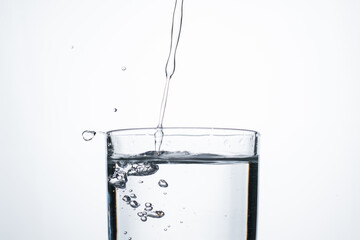 Jet of water or alcohol is pouring into a glass with splashes and bubbles, copy space