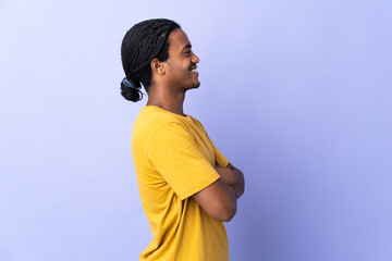 Young African American man with braids man isolated on purple background in lateral position