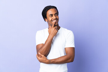 Young African American man with braids man isolated on purple background having doubts while looking up