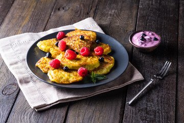 Vegetable vegetarian pumpkin pancakes with yogurt, blueberries and raspberries on a wooden background, summer food, delicious snacks. Pumpkin pancakes. Healthy food concept
