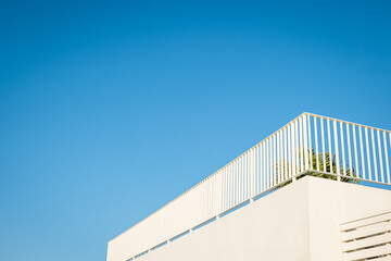 White terrace with metal railing under blue sky