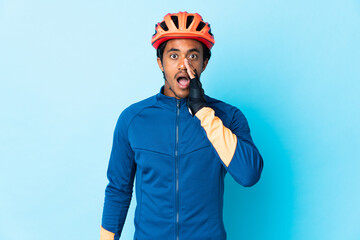 Young cyclist man with braids over isolated background shouting with mouth wide open