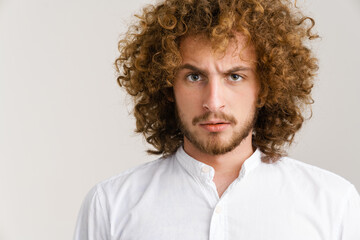 Fototapeta na wymiar Young curly man with ginger hair frowning and looking at camera