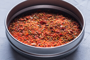 Red dried crushed hot chili peppers and chili flakes or powder in bowl on grey background.