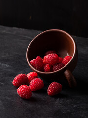 Fresh ripe raspberries in a cup on dark background.