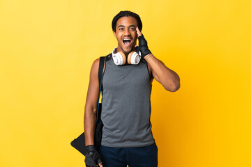 Young sport African American man with braids with bag isolated on yellow background with surprise and shocked facial expression