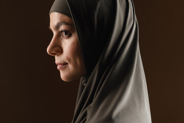 Young muslim woman in hijab looking aside while posing in profile