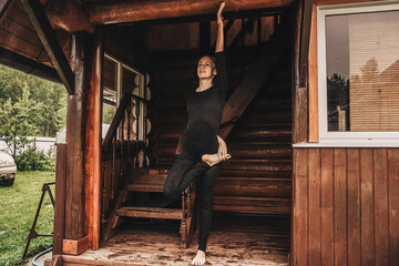 Woman doing yoga in veranda. Rainy day.