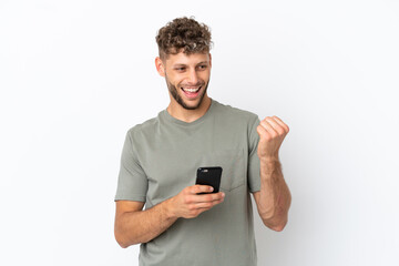 Young caucasian handsome man isolated on white background with phone in victory position