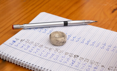 Drawing of a notebook with multiplication tables written by a little girl. Concept of back to school, homework, learning math.