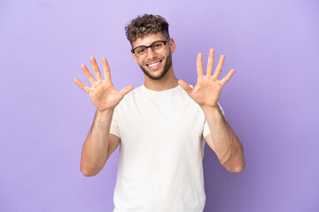Naklejka premium Delivery caucasian man isolated on purple background counting ten with fingers