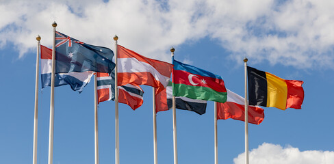 Flags on flagpoles, against a cloudy sky. Flags of various countries of the world flutter in the...
