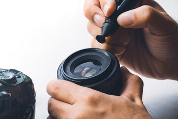 Human hand cleaning stain on camera optical lens with carbon brush cleaner