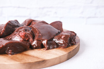 Raw liver on a chopping board on table .