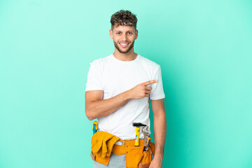 Young electrician blonde man isolated on green background pointing finger to the side