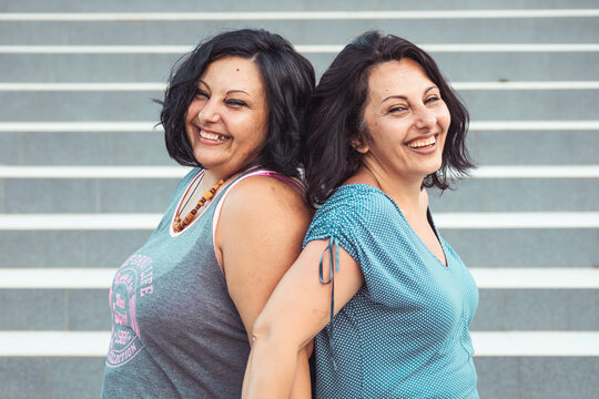 Portrait of two adult brunette twin sisters. Different styles