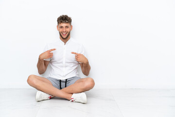 Fototapeta na wymiar Young blonde man sitting on the floor isolated on white background with surprise facial expression