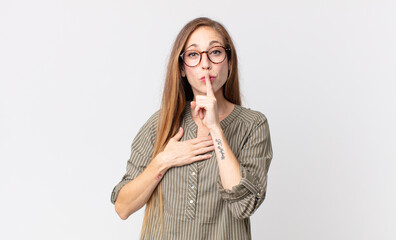 pretty thin woman looking serious and cross with finger pressed to lips demanding silence or quiet,...