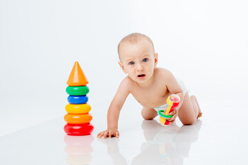 a baby boy with a multi-colored pyramid crawling , isolated on a white background;