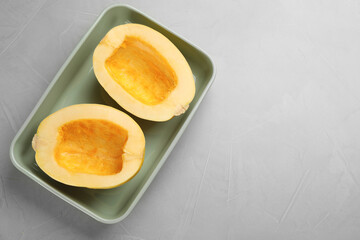 Naklejka na ściany i meble Raw spaghetti squash halves in baking dish on light table, top view. Space for text