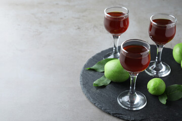 Delicious liqueur and green walnuts on grey table. Space for text