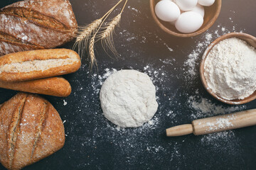 Bakery - gold rustic loaves of bread and flour on black chalkboard background. 