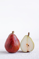 Ripe organic red pear and slices of pear on white stone background. Fresh pear closeup.