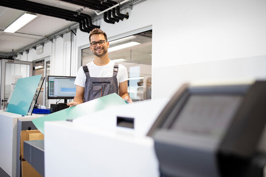 Portrait Of Smiling Print Worker Standing By Computer To Plate Machine In Print Shop.