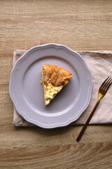 Slice of cheese and leek quiche on wooden table. Flat lay.