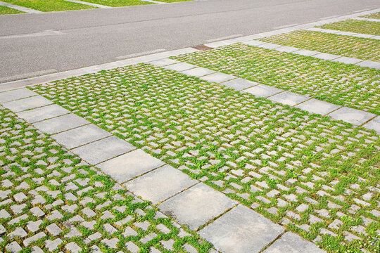 Grey concrete flooring blocks assembled on a substrate of sand with grass - type of flooring permeable to rain water as required by the building laws used for sidewalks and parking areas