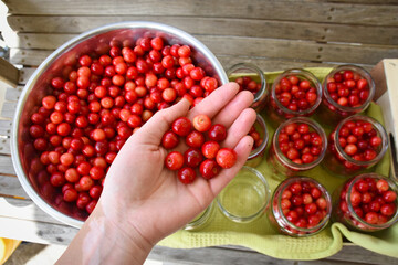 Cherry compote being prepared for winter preservation in a big pot on a stove, where all bacteria is destroyed because of heat.