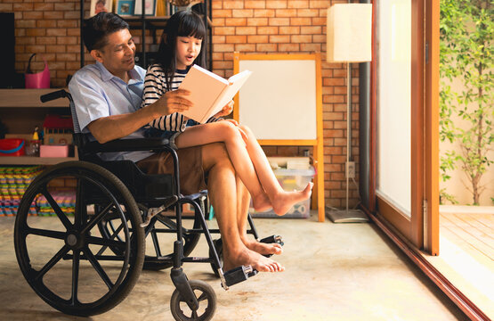 Senior male smiling and reading interesting fairytale to curious girl while sitting on wheelchair and resting together. - Powered by Adobe