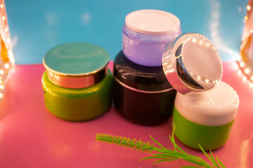 Different makeup cosmetics and accessories on a pink and blue background.