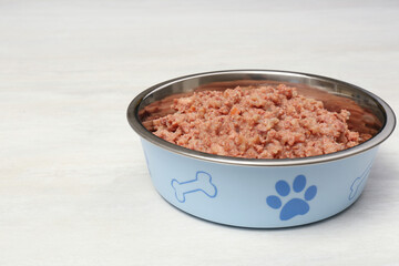 Wet pet food in feeding bowl on white table
